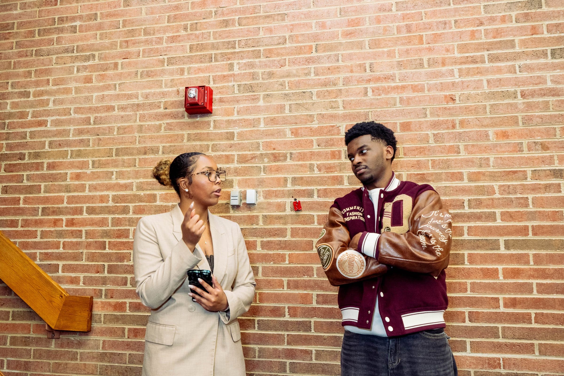 Two attendees in conversation near a brick wall during the Howard University symposium.